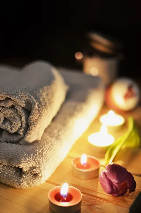 Rolled towels and lit candles on a massage table